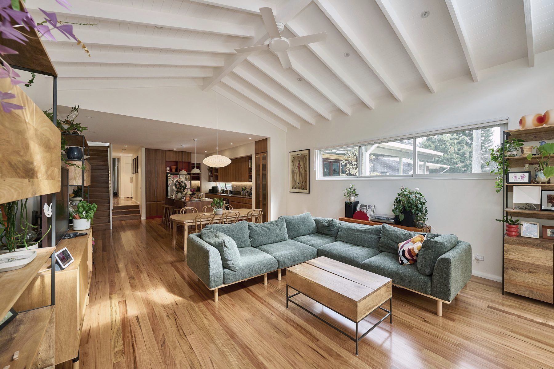 Living room under a raked timber-lined ceiling, opening to the garden
