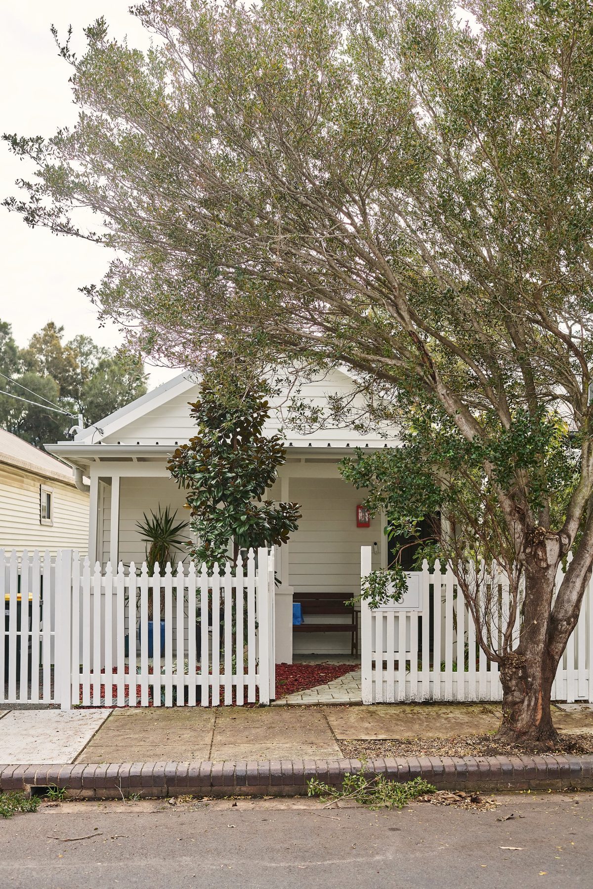Weatherboard cottage behind a white picket fence